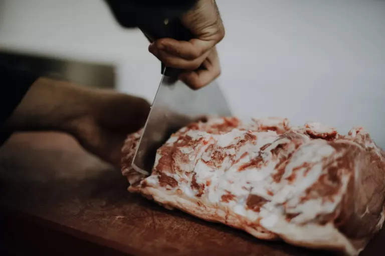 Persona cortando carne cruda