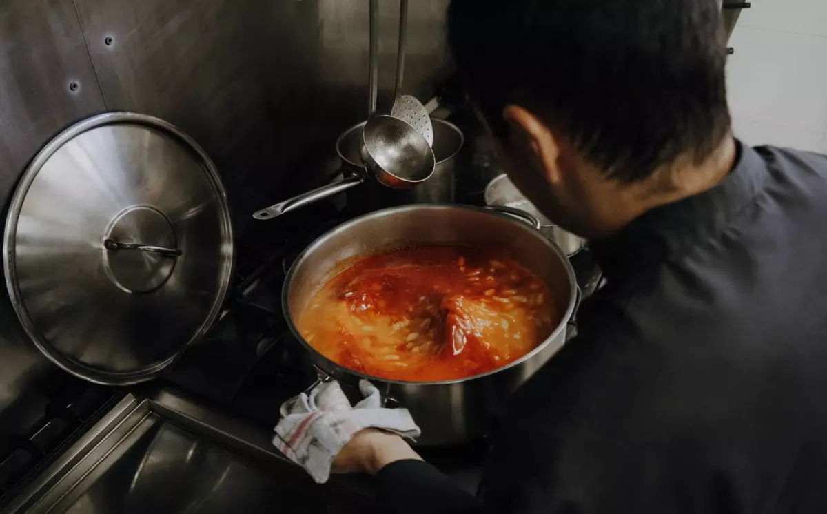 Cocinero removiendo olla con fabada asturiana
